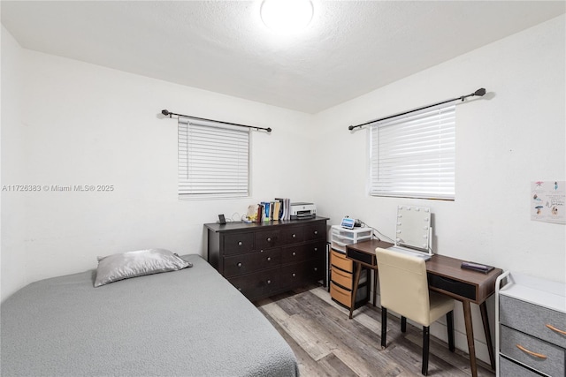 bedroom featuring a textured ceiling and light hardwood / wood-style flooring