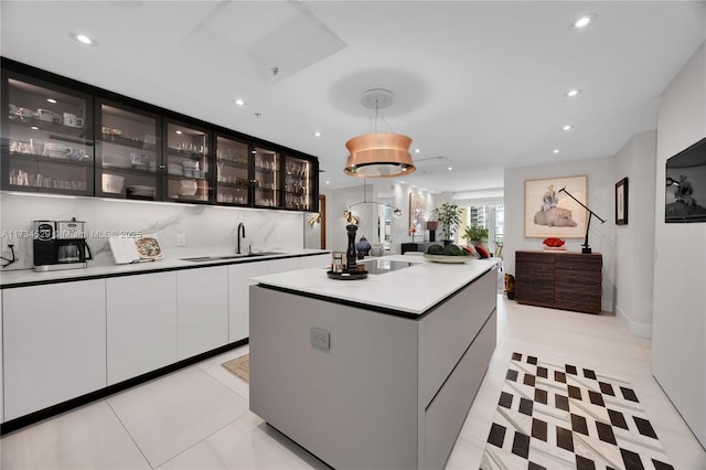 kitchen with white cabinetry, sink, a center island, and pendant lighting