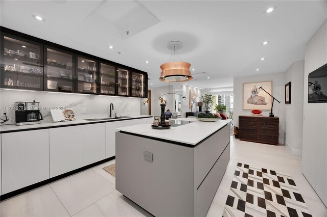 3400 SW 27th Ave Unit 704, Miami, FL 33133 - kitchen with recessed lighting, glass insert cabinets, white cabinets, a center island, and light countertops