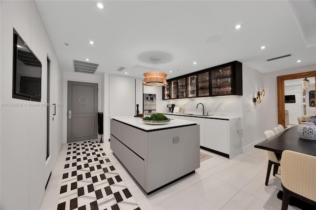 kitchen with sink, white cabinetry, hanging light fixtures, dark brown cabinetry, and a kitchen island