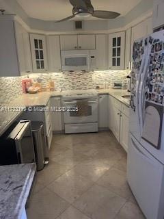 kitchen with white cabinets, decorative backsplash, ceiling fan, breakfast area, and white appliances