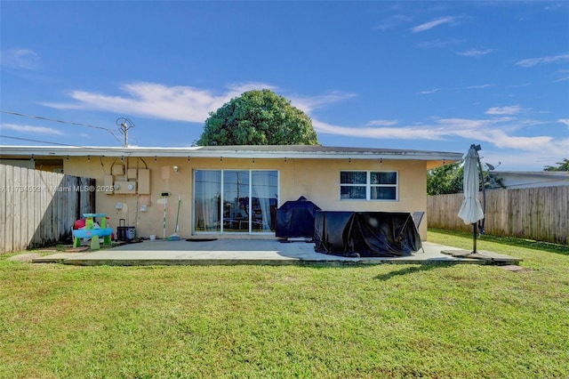 back of property with a yard and a patio