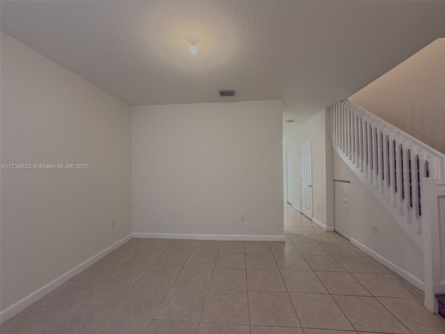 empty room featuring light tile patterned floors and a textured ceiling