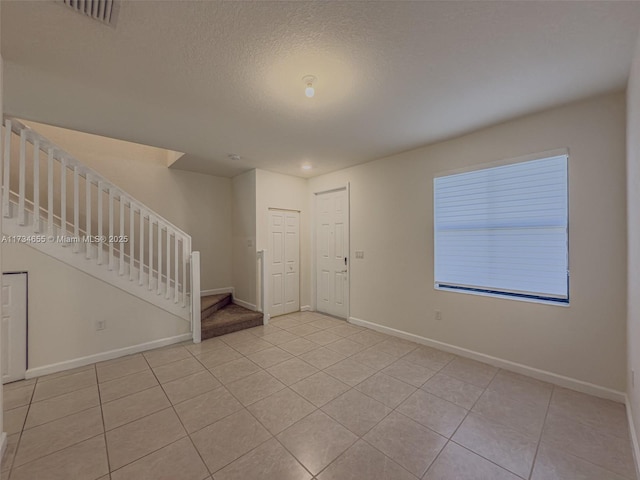 spare room with a textured ceiling and light tile patterned floors