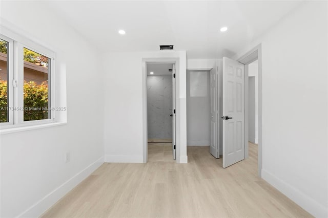 unfurnished bedroom featuring ensuite bath and light hardwood / wood-style flooring