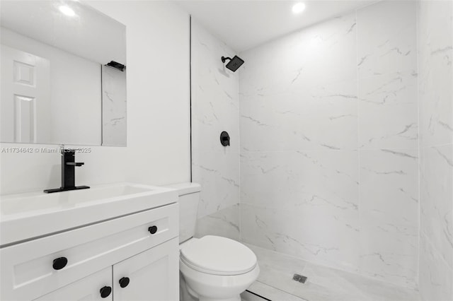 bathroom featuring vanity, toilet, and a tile shower