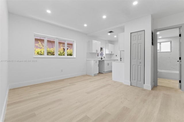 unfurnished living room featuring sink and light wood-type flooring