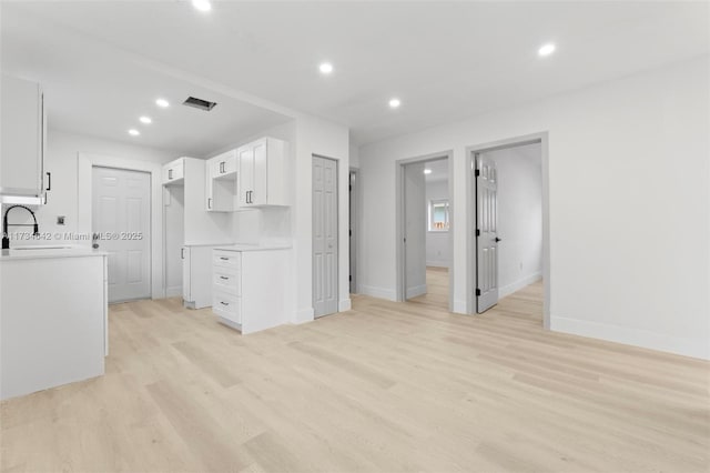 kitchen with sink, light hardwood / wood-style flooring, and white cabinets