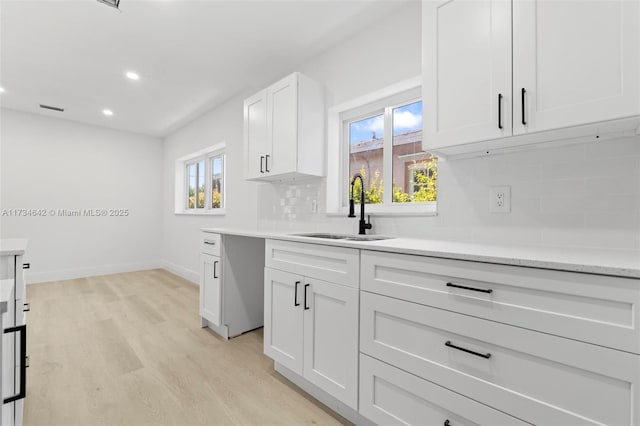 kitchen with sink, a wealth of natural light, white cabinets, and backsplash