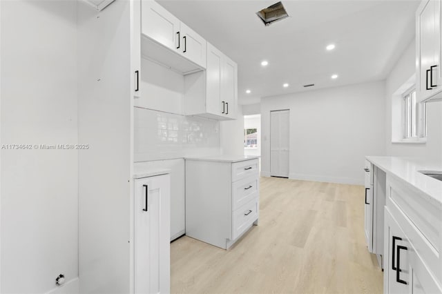 kitchen featuring tasteful backsplash, white cabinetry, and light wood-type flooring