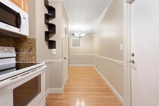 hallway featuring crown molding, light hardwood / wood-style floors, and a notable chandelier