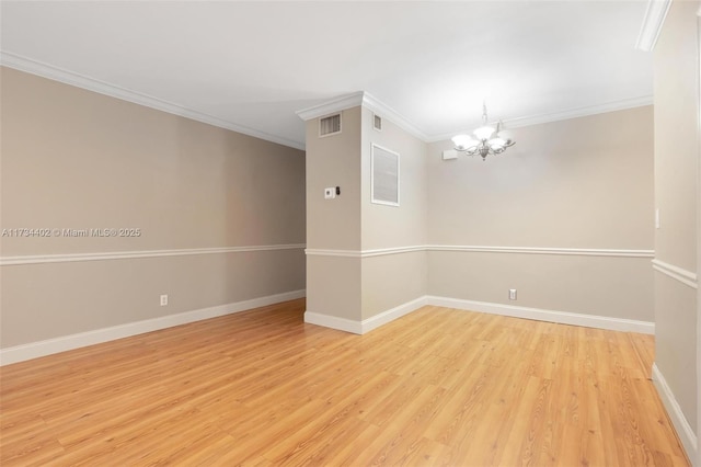 spare room with ornamental molding, an inviting chandelier, and light hardwood / wood-style flooring