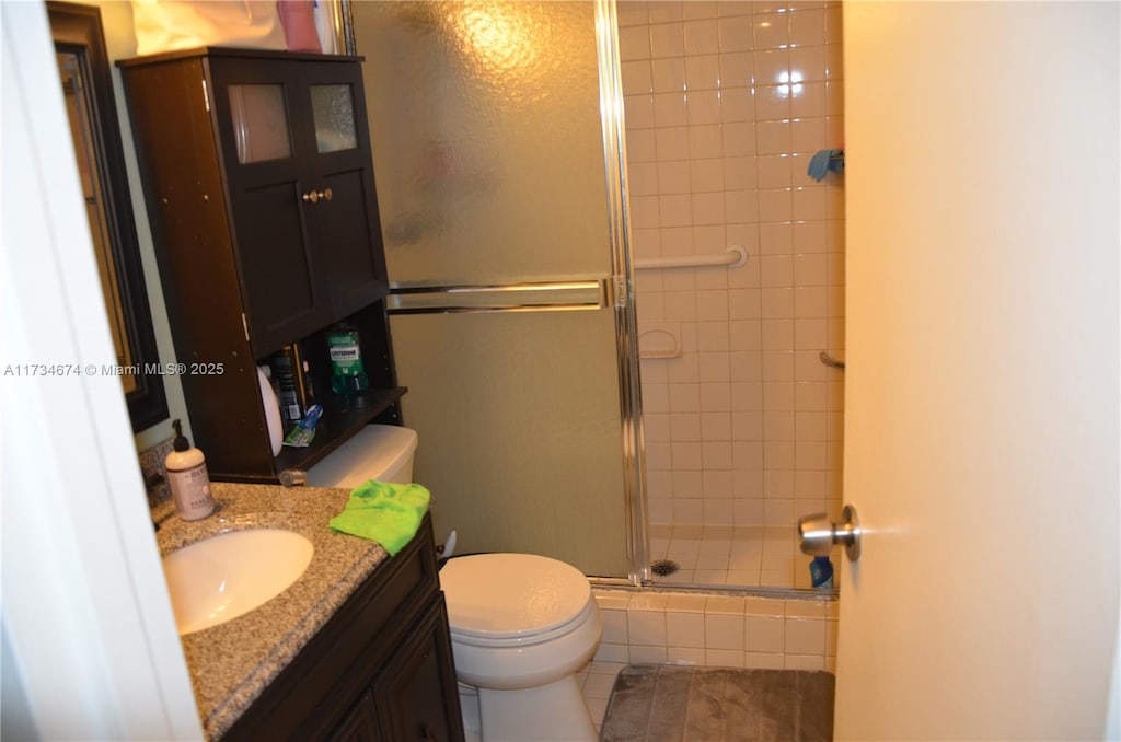 full bath with a stall shower, vanity, and toilet