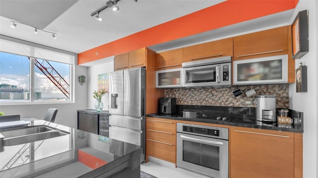 kitchen featuring stainless steel appliances, sink, track lighting, and backsplash