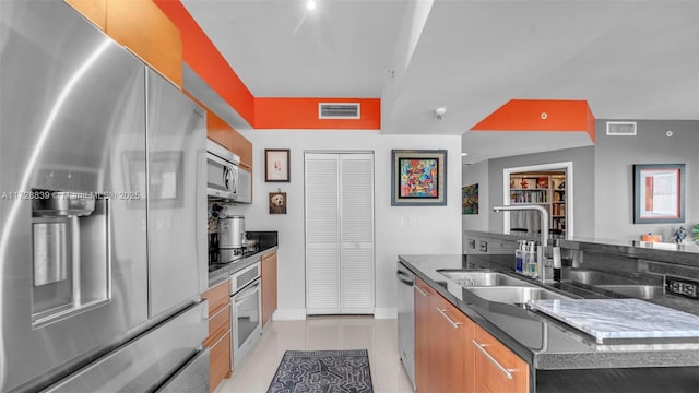 kitchen featuring a kitchen island, appliances with stainless steel finishes, sink, dark stone countertops, and light tile patterned floors