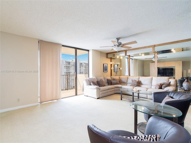 living room featuring ceiling fan, light colored carpet, a wall of windows, and a textured ceiling