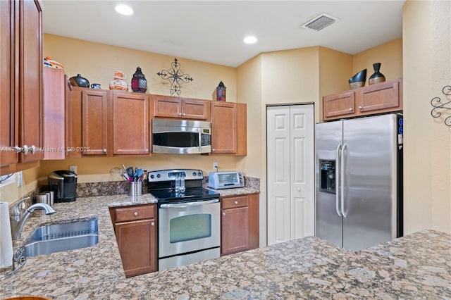 kitchen featuring sink, light stone countertops, and appliances with stainless steel finishes