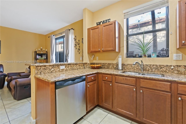 kitchen with sink, stainless steel dishwasher, light tile patterned floors, kitchen peninsula, and light stone countertops