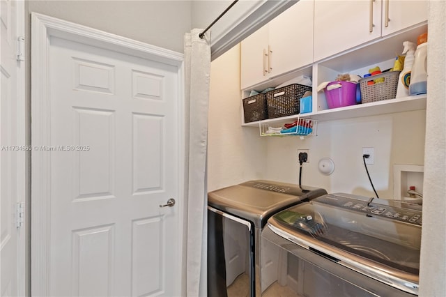 washroom featuring cabinets and washer and clothes dryer