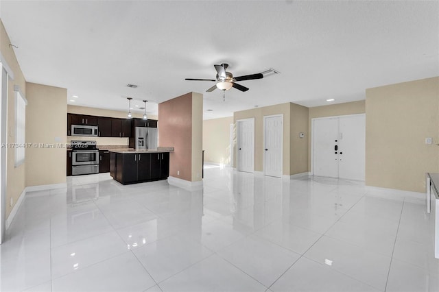 kitchen featuring light tile patterned floors, ceiling fan, appliances with stainless steel finishes, dark brown cabinets, and a kitchen island