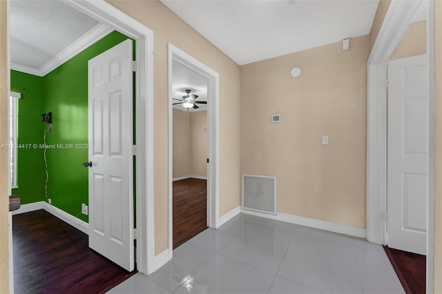 corridor with light tile patterned floors, ornamental molding, and a textured ceiling