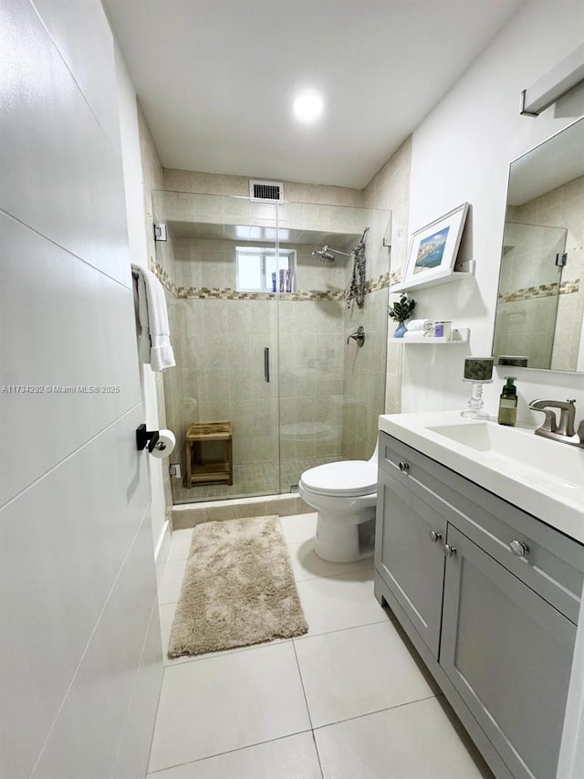 bathroom featuring vanity, tile patterned flooring, a shower with door, and toilet