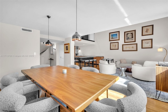 dining area with visible vents, light wood-style floors, and stairs