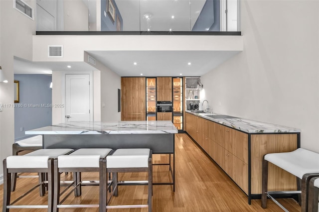 kitchen with light wood-type flooring, visible vents, modern cabinets, and a sink