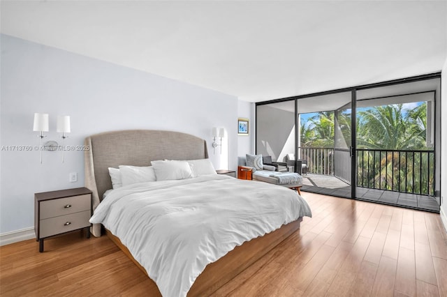 bedroom with a wall of windows, access to outside, and wood finished floors