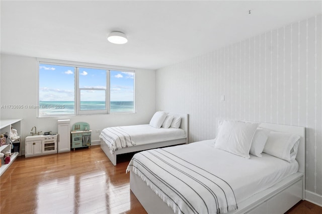 bedroom with a water view and light hardwood / wood-style flooring