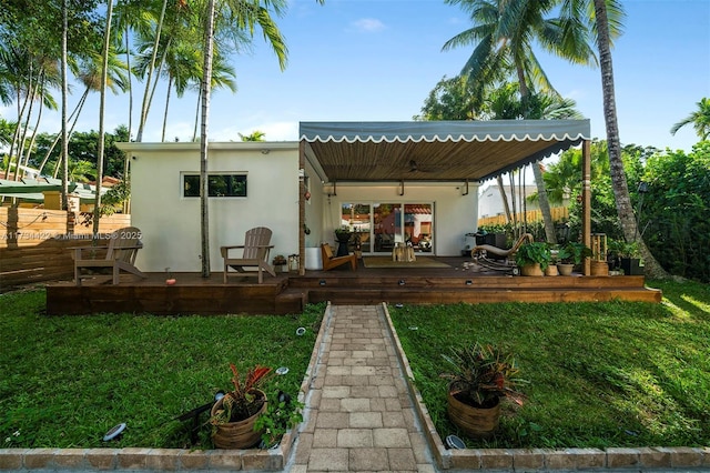 back of property featuring a wooden deck and a yard