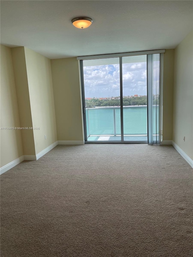 empty room featuring expansive windows, a water view, and carpet floors