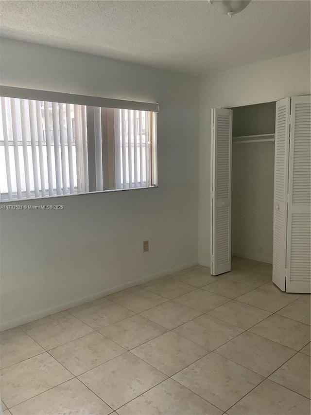 201 178th Dr Unit 309, Sunny Isles Beach, FL 33160 - unfurnished bedroom with tile patterned flooring, a closet, and a textured ceiling