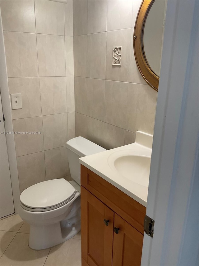 bathroom with tile walls, vanity, tile patterned floors, and toilet