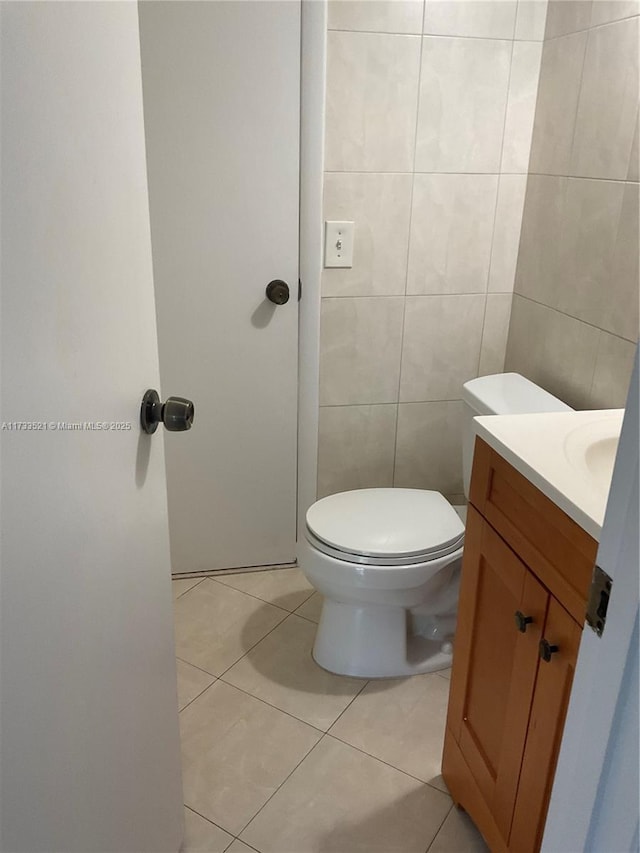 bathroom featuring vanity, tile patterned flooring, tile walls, and toilet