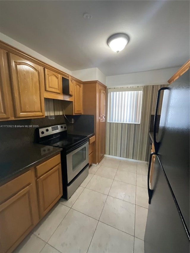 201 178th Dr Unit 309, Sunny Isles Beach, FL 33160 - kitchen with light tile patterned floors, freestanding refrigerator, dark countertops, brown cabinetry, and stainless steel electric stove