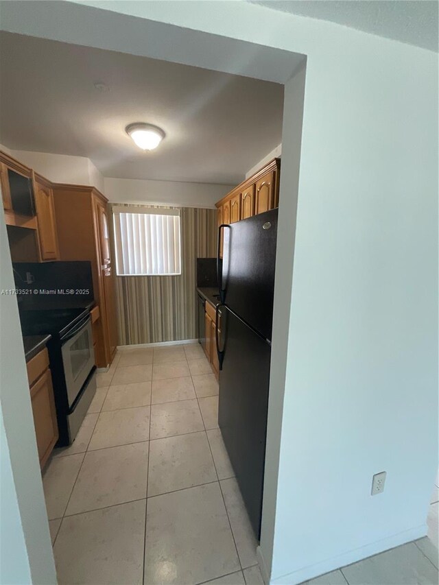 201 178th Dr Unit 309, Sunny Isles Beach, FL 33160 - kitchen featuring dark countertops, freestanding refrigerator, light tile patterned flooring, and range with electric stovetop