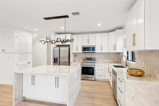 kitchen with sink, white cabinetry, a center island, hanging light fixtures, and appliances with stainless steel finishes