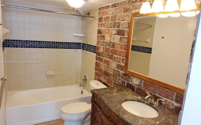 full bathroom with tiled shower / bath combo, vanity, a textured ceiling, brick wall, and toilet