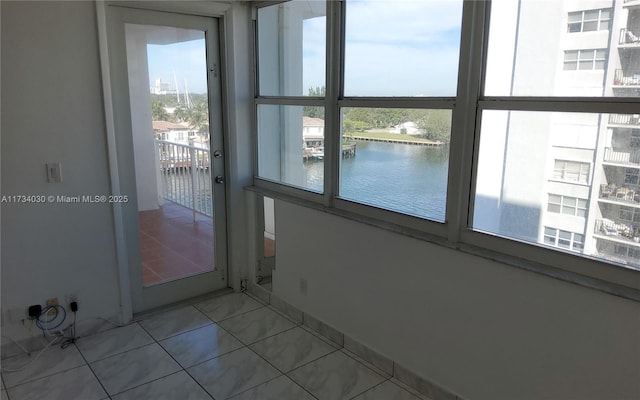 doorway featuring a water view, light tile patterned floors, and a wealth of natural light