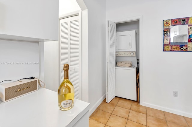 washroom featuring stacked washing maching and dryer and light tile patterned flooring