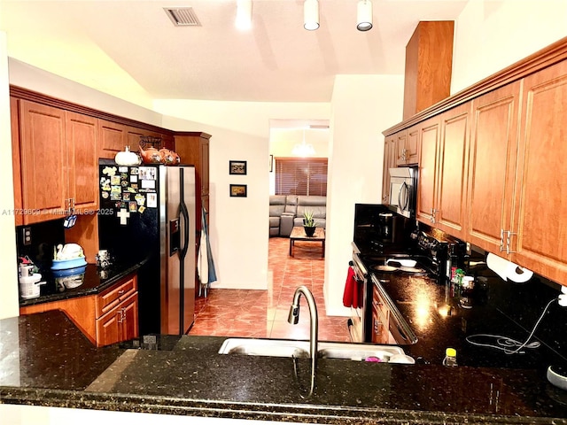 kitchen with appliances with stainless steel finishes, sink, kitchen peninsula, and dark stone counters