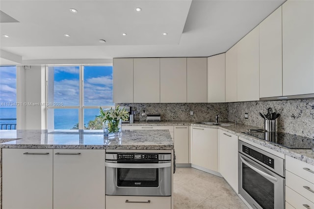 kitchen featuring white cabinets, a water view, oven, and black electric cooktop