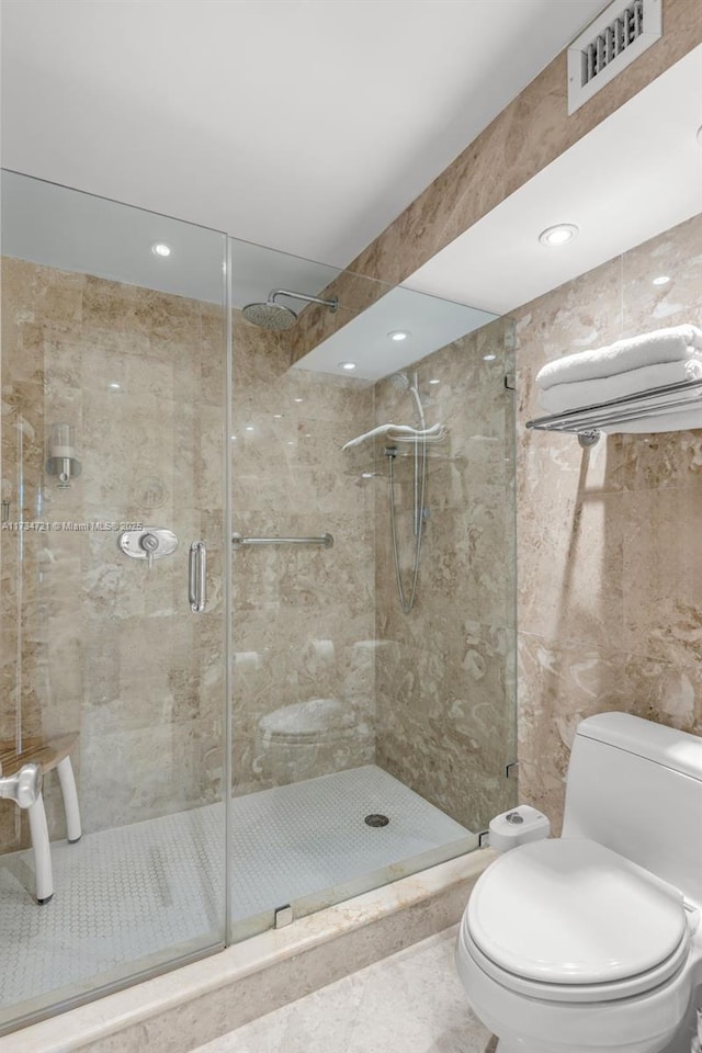 bathroom featuring tile patterned floors, a shower with door, and toilet