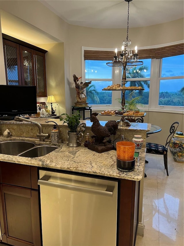 kitchen featuring sink, a chandelier, stainless steel dishwasher, dark brown cabinetry, and light stone countertops