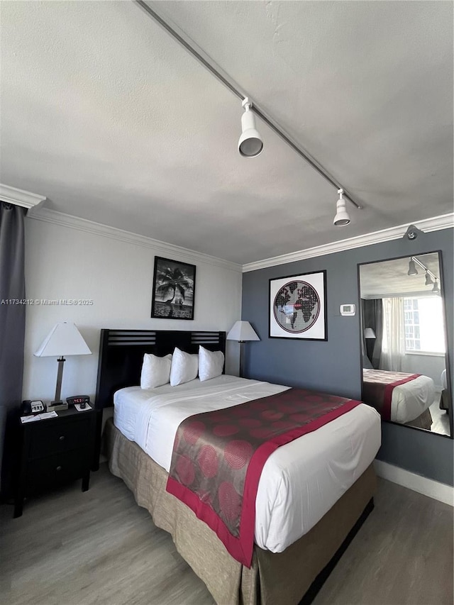 bedroom featuring crown molding, track lighting, and wood-type flooring