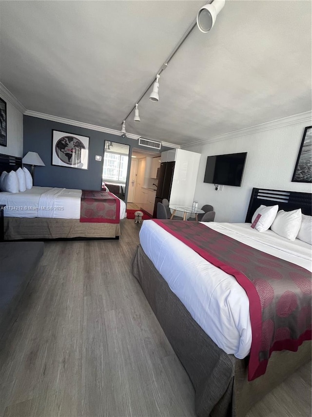 bedroom featuring crown molding, hardwood / wood-style flooring, and track lighting