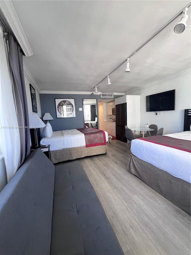 bedroom with crown molding, wood-type flooring, and track lighting