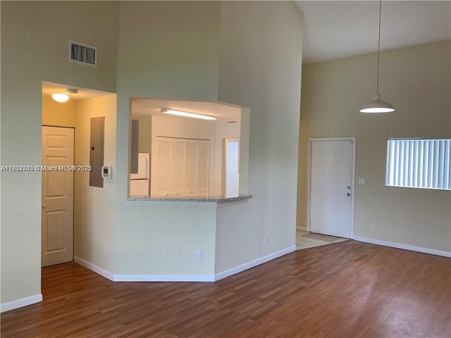 unfurnished living room featuring wood-type flooring and a high ceiling