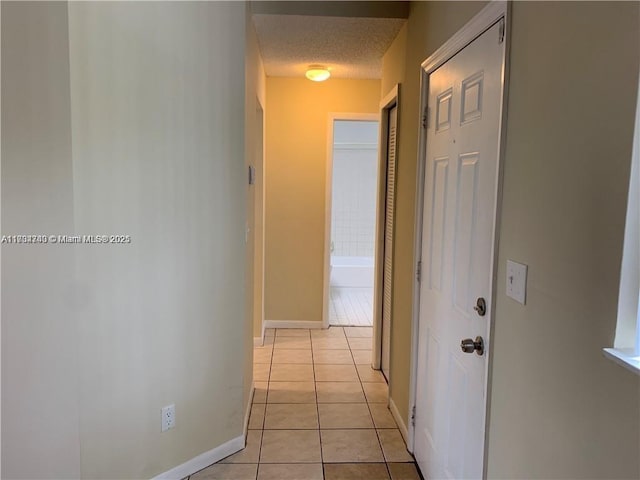 hall featuring light tile patterned floors and a textured ceiling